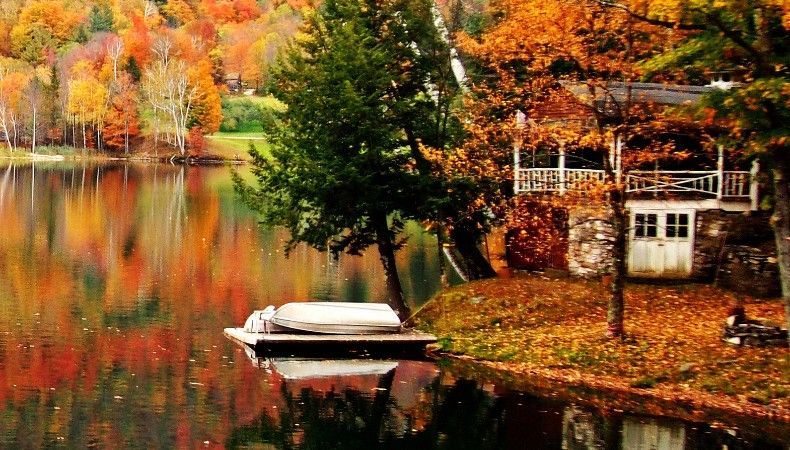 Vermont lakefront property with a dock, boat, and fall foliage along the shoreline.